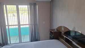 a bedroom with a bed and a large window at Apartamento no Centro Proximo a Tudo in Barra do Garças +9 photos