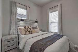 a white bedroom with a bed and two windows at Downtown - Colorado Cool - Relaxing and Quiet in Colorado Springs