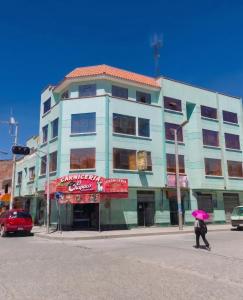 a woman with a pink umbrella walking in front of a building at Sunset - Puesta de Sol in Uyuni
