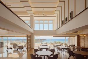 a restaurant with tables and chairs and a view of the ocean at Anse Yomitan Toya in Yomitan