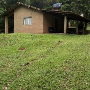 a house with a grassy yard in front of it at Chácara chalé in Juquitiba