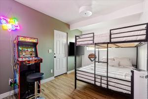 a bedroom with two bunk beds and a pinball machine at Poolside Paradise Big Backyard Arcade Mural in Mesa