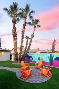 a group of chairs and palm trees in front of a mural at Poolside Paradise Big Backyard Arcade Mural in Mesa