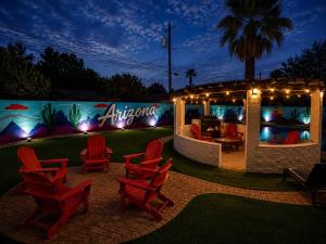 a group of red chairs sitting in front of a building at Poolside Paradise Big Backyard Arcade Mural in Mesa