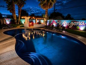 a swimming pool in a resort at night at Poolside Paradise Big Backyard Arcade Mural in Mesa