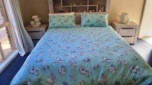 a bedroom with a bed with a blue comforter at Cassana In The Cove in North Arms Cove +10 photos