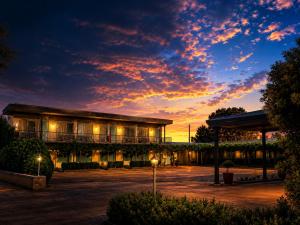 a building with a sunset in the background at Memphis Motor Inn- UNDER NEW MANAGEMENT in Parkes