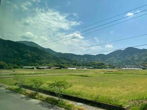 a view of a field with mountains in the background at Rita HOSTEL in Itoshima