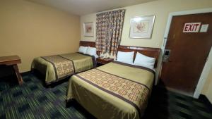 a hotel room with two beds and a desk at Slumberland Motel Mount Holly in Mount Holly