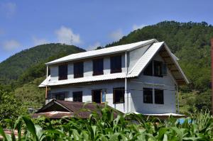 a white house with windows in front of a mountain at Agape Log Cabin in Sagada