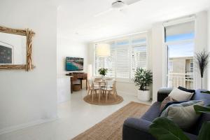 a living room with a blue couch and a table at Avalon Beachside Apartment Pool Beach Access in Avalon