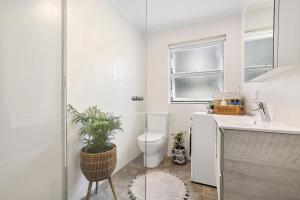 a white bathroom with a toilet and a sink at Avalon Beachside Apartment Pool Beach Access in Avalon