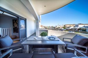 a patio with a table and chairs on a balcony at Higher Ground on Seaview - Rooftop Coastal Escape in Henley Beach South