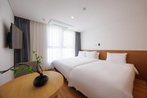 a hotel room with two beds and a table at Kenny Stay Busan Gijang in Busan +31 photos