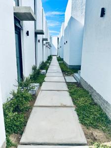 a walkway between two white buildings with grass at Casa RuMat in Swakopmund