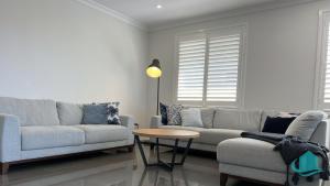 a living room with two couches and a table at Beachside Oasis in Caves Beach