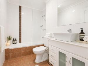 a bathroom with a toilet and a sink and a tub at Relaxing 2BR Split-Level Home in Wahroonga in Waitara +3 photos