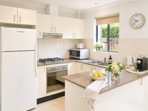 a kitchen with white cabinets and a white refrigerator at Relaxing 2BR Split-Level Home in Wahroonga in Waitara
