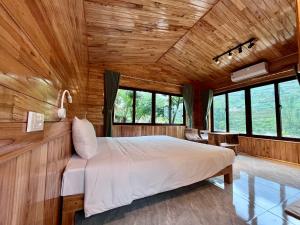 a bedroom with a white bed in a wooden wall at Zay Riverside House in Tả Van