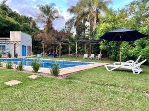a pool with an umbrella and two chairs and a table and an umbrella at Villa Dona Jaca - Casa da Mata - 01 in Socorro
