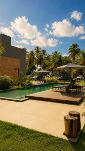 a pool with benches and umbrellas in a park at Estúdio Premium em Japaratinga - Unidade Coralli - Vila Naluri in Japaratinga