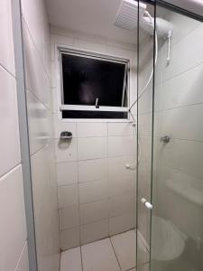 a shower with a glass door and a window at Apartamento 2 quartos ,Mobiliado em Sumare SP in Sumaré