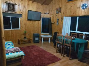 a living room with wooden walls and a table and chairs at Cabaña Chaicura in Ancud