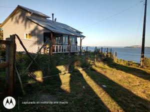 a house with a fence in front of the ocean at Cabaña Chaicura in Ancud