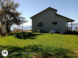 a house on a grassy yard with a tree at Cabaña Chaicura in Ancud