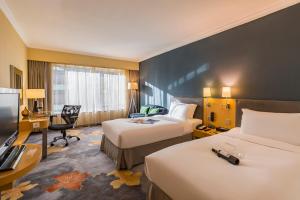 a hotel room with two beds and a desk at Beijing New World Centre Tongpai Hotel in Beijing