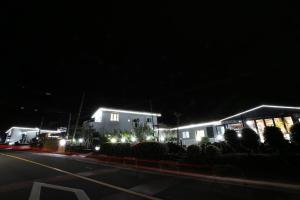 a street at night with buildings and lights at Maple Happy House Jeju in Jeju