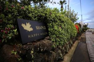 a sign for a happy house on a bush at Maple Happy House Jeju in Jeju
