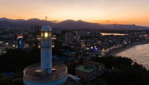 Ein Leuchtturm, der nachts über einer Stadt thront. in der Unterkunft Cocomo Spa in Sokcho