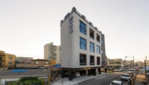 ein hohes weißes Gebäude in einer Stadtstraße mit Autos in der Unterkunft Cocomo Spa in Sokcho