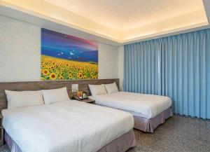 due letti in una stanza d'albergo con un dipinto sul muro di 台中逢甲豐和立hotel商旅 台中休息平日499起 台中出差統編可 台中團體訂房 台中國民旅遊卡訂房 台中包層 台中包棟 電視可看youtube 可停遊覽車自費 a Taichung