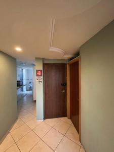 a hallway with a brown door and a tile floor at apartamento aconchego 01 in Divinópolis