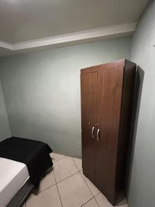 a bedroom with a bed and a wooden cabinet at apartamento aconchego 01 in Divinópolis