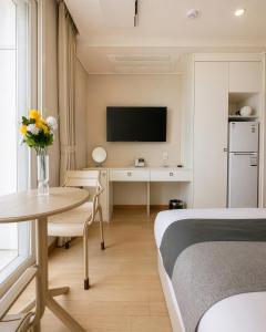 a hotel room with a bed and a desk with a tv at Gangneung Top Ocean in Gangneung