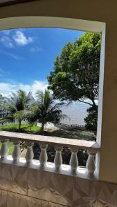 a window with a view of the ocean and palm trees at Casarão da ilha in Ilha Cotejuba +3 photos
