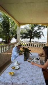 a man and woman sitting at a table with food at Casarão da ilha in Ilha Cotejuba