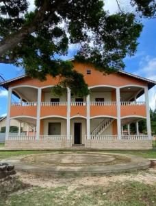 a large orange building with a tree in front of it at Casarão da ilha in Ilha Cotejuba