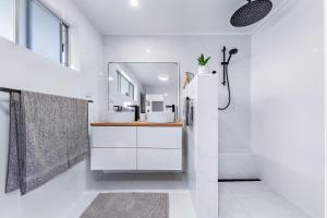 a white bathroom with a sink and a mirror at Hillcrest Harmony in Airlie Beach
