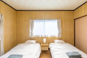 two beds in a room with a window at もくハウス in Kamifukuoka