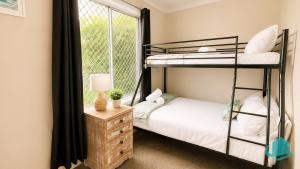 a bedroom with two bunk beds and a window at Beachside Cottage at Blacksmiths in Blacksmiths
