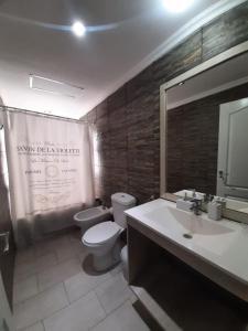 a bathroom with a toilet and a sink and a mirror at Ñande Roga San Cemente in San Clemente del Tuyú