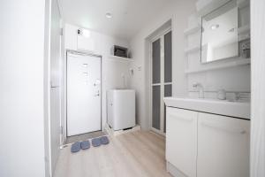 a kitchen with white cabinets and a white refrigerator at Grace Shintoshin in Saitama
