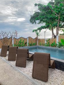 a group of chairs sitting next to a swimming pool at RATU Village - Luxury Island Apartment & Private Villa Gili Air in Gili Islands