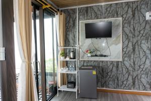 a living room with a television on a wall at บ้านนุสรา รีสอร์ท ภูทับเบิก in Ban Maeo Thap Boek