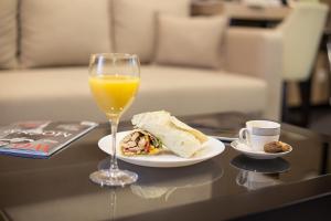 een glas sinaasappelsap en een bord eten en drinken bij Dominic Smart & Luxury Suites - Republic Square in Belgrado