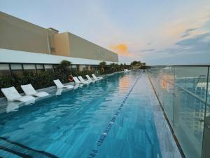 a swimming pool with white chairs and a building at The Song - Vitamin Sea & Sun - Căn Hộ Cao Cấp và Sự Lựa Chọn Tốt Nhất in Vung Tau